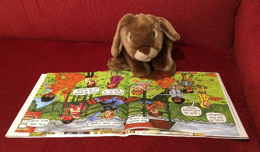 Caramel is looking at one of the fun pages in My Teacher is a Robot where the kids are all in the school playground and are being attacked by the mud monsters. 