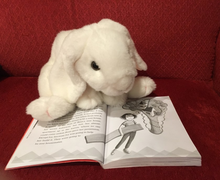 Marshmallow is pointing at the pages in Ivy and Bean Make the Rules where Bean is planning to make her tree house.