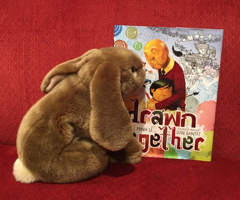 Caramel is looking at the front cover of Drawn Together, written by Minh Le and illustrated by Dan Santat. 