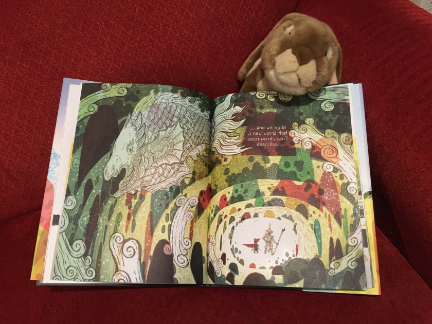 Caramel is pointing to some of the artwork that the boy and his grandpa create together in  Drawn Together, written by Minh Le and illustrated by Dan Santat. 