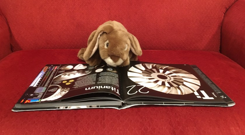 Caramel is reading about Titanium, one of his favorite elements, in  The Elements: A Visual Exploration of Every Known Atom in the Universe by Theodore Gray. 