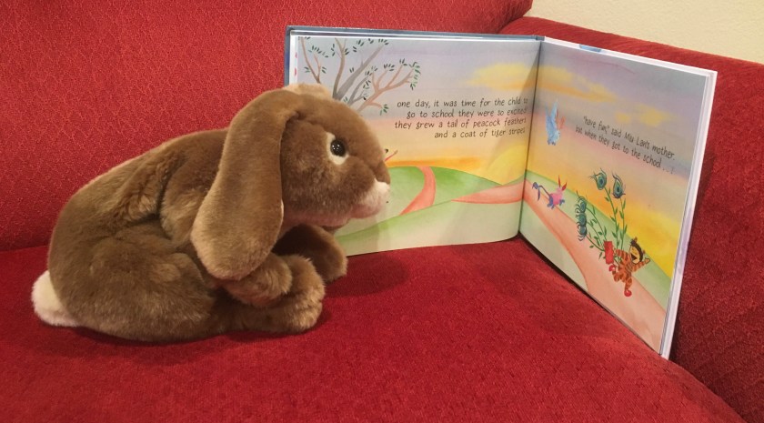 Caramel is looking at the pages in From the Stars in the Sky to the Fish in the Sea (written by Kai Cheng Thom and illustrated by Wai-Yant Li and Kai Yun Ching) where Miu Lan is going to school for the first time and they are so excited that "they grew a tail of peacock feathers and a coat of tiger stripes".