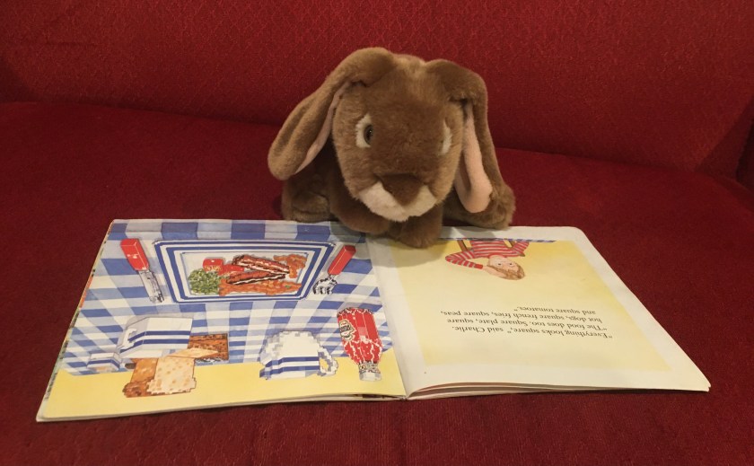 Caramel is reading The Boy with Square Eyes by Juliet Snape and Charles Snape. He is on the page when Charlie tells his mom, "Everything looks square. The food does, too. Square plate, square hot dogs, square french fries, square peas, and square tomatoes."