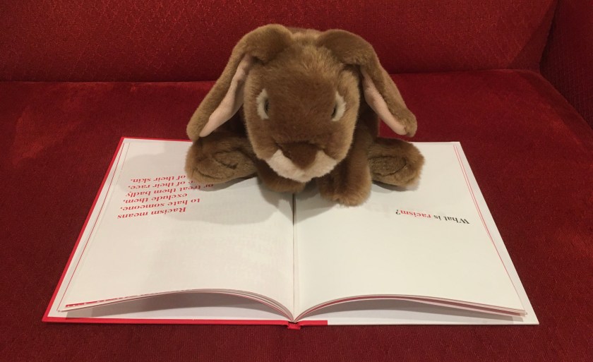 Caramel is rereading the definition of racism in A Kids Book About Racism by Jelani Memory.