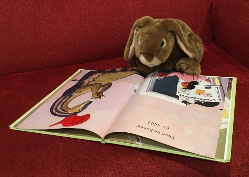 Caramel is reading How Do Dinosaurs Eat Their Food? (2005),  written by Jane Yolen and illustrated by Mark Teague. 
