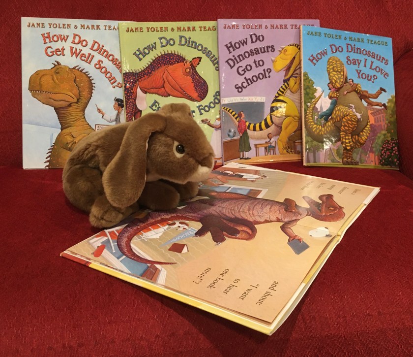 Caramel is reading How Do Dinosaurs Say Good Night? (2000),  written by Jane Yolen and illustrated by Mark Teague. 