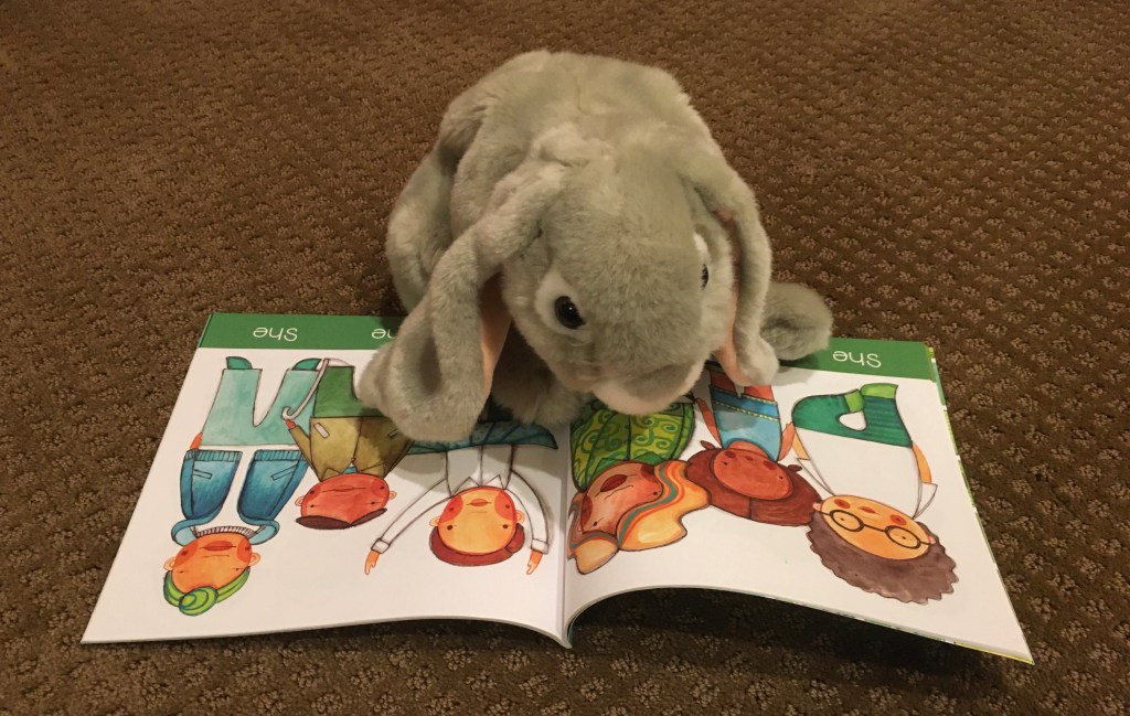 Sprinkles is reading the page in They, She, He, Me: Free To Be! by Maya Gonzalez and Matthew Smith-Gonzalez that display various ways of being a "she". 