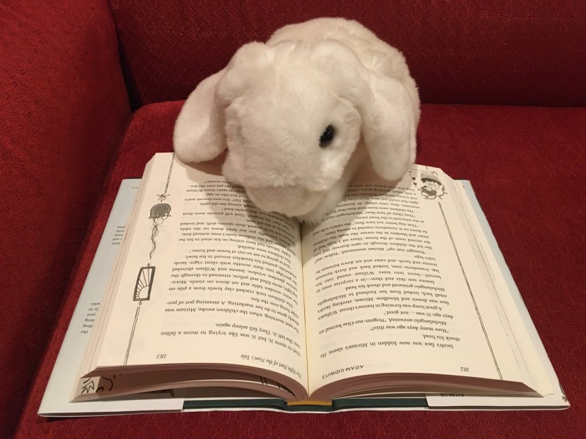 Marshmallow is reading The Inquisitor's Tale: Or, The Three Magical Children and Their Holy Dog, written by Adam Gidwitz and illuminated by Hatem Aly. 