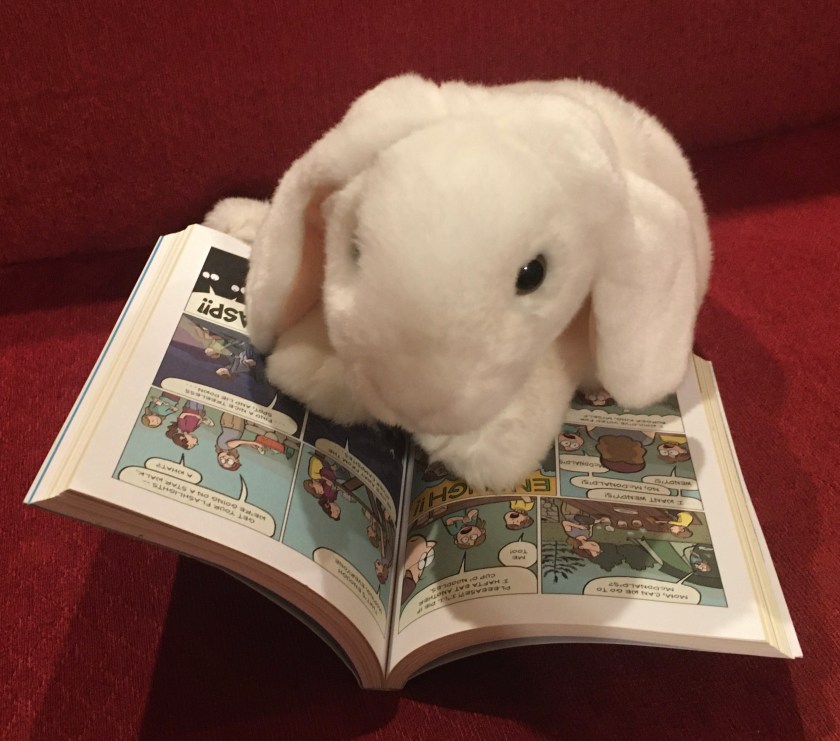 Marshmallow is reading Sisters by Raina Telgemeier.