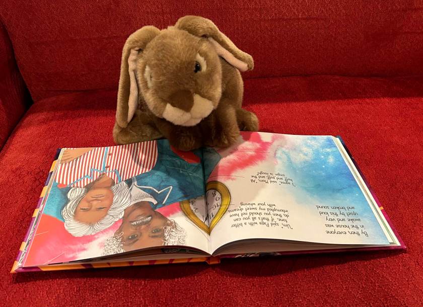 Caramel is reading Somebody to Love written by Valerie June and illustrated by Marcela Avelar.