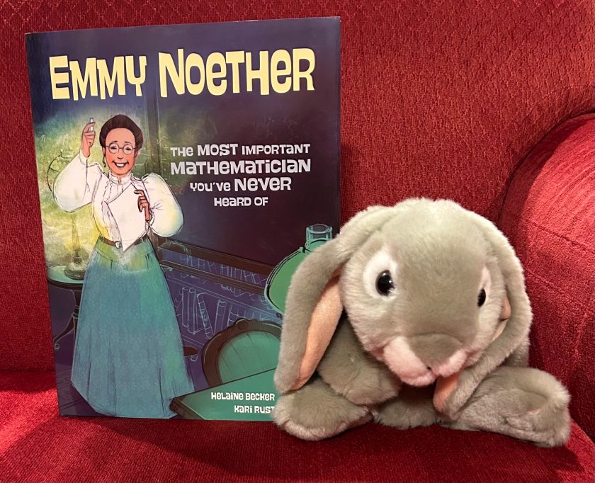 Sprinkles is posing with Emmy Noether: The Most Important Mathematician You've Never Heard Of, written by Helaine Becker and illustrated by Kari Rust.