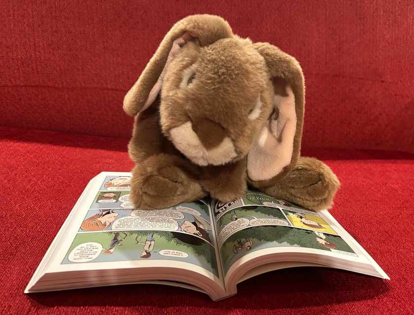 Caramel is reading Evil Spy School: The Graphic Novel, written by Stuart Gibbs and illustrated by Anjan Sarkar.