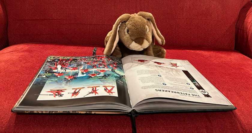 Caramel and Aeldari friend are reading and enjoying Warhammer 40000: Core Book.