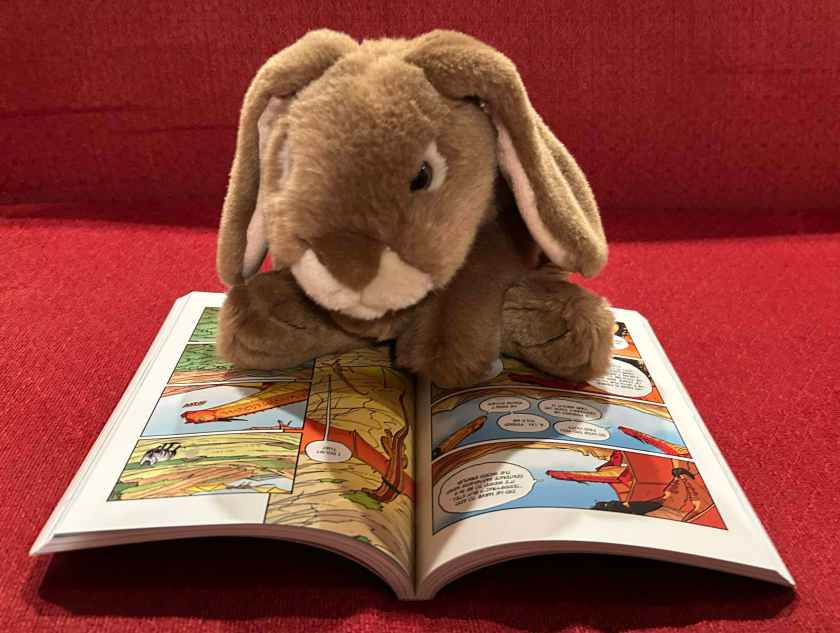 Caramel is reading Escaping Peril: The Graphic Novel (Book Eight of Wings of Fire), written by Tui Sutherland and illustrated by Mike Holmes.