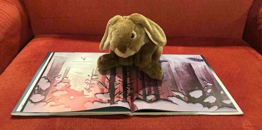 Caramel is reading The Wild Robot on the Island: An Illustrated Picture Book Adaptation of The Wild Robot, written and illustrated by Peter Brown.