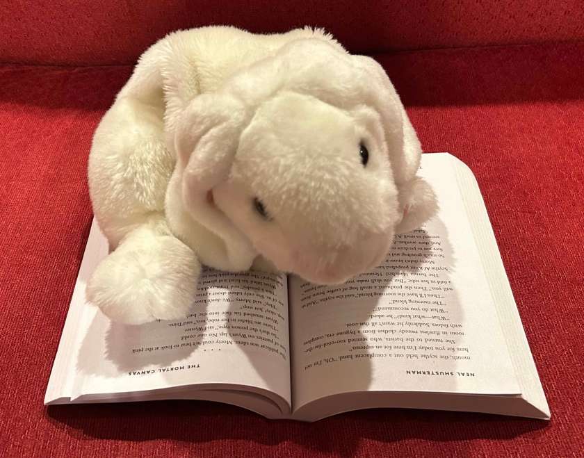 Marshmallow is reading Gleanings: Stories from the Arc of a Scythe by Neal Shusterman.